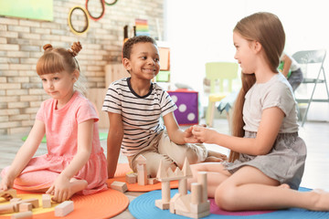 Sticker - Cute little children playing with wooden blocks indoors