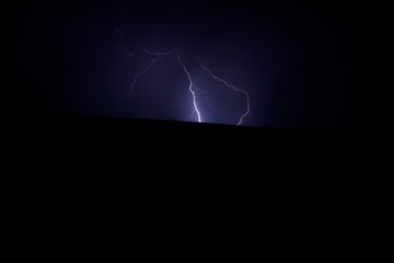 Single lightning strike in nature in a field with colours of white and blue electricity and no buildings in the landscape image