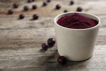 Bowl with acai powder on wooden table