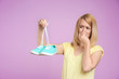 Young woman with stinky shoes on color background. Air freshener