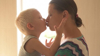 happy young mother is playing with her beautiful little boy. baby caress, kissing, hugging, coquetry