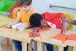 © weedezign - African american boy kid with sadness emotion sitting in classroom in kindergarten preschool.bulying depression concept.