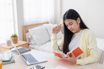 Poster - Asian female freelancer headache and stress while working on paperwork with laptop on table in bedroom at home.Work at home concept.work from home concept.