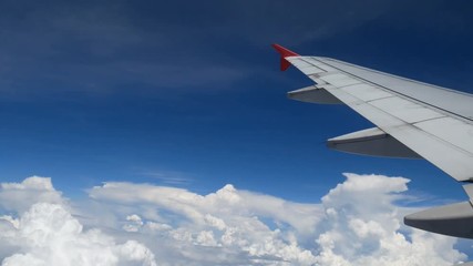 Wall Mural - 4K footage airplane flight. wing of an airplane flying above the white clouds and blue sky. beautiful aerial view from the window of the plane on travelling time by aircraft. holiday , vacation time