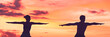 © Maridav - Yoga people training meditating in warrior pose at sunset background panoramic banner. Silhouette of healthy athletes.