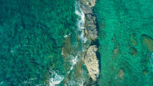 Top Aerial View Of The Shallow Turquoise Transparent Water With Rocks.