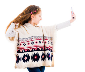 Wall Mural - Teenage girl with long hair in poncho making a selfie isolated on white background. Girl taking pictures of herself using smartphone