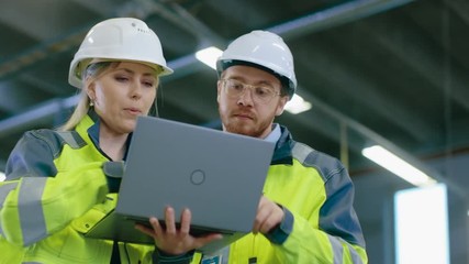 Poster - Male and Female Industrial Engineers Work on a Manufacturing Plant, They Discuss Project, Point in the Direction of the Machinery while Using Laptop. In the Background Industrial Manufacturing Plant.