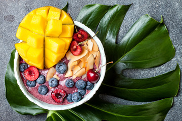 Poster - Acai breakfast superfoods smoothie bowl with mango, blueberry, cherry, coconut flakes. Overhead, top view, flat lay.