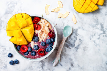 Poster - Acai breakfast superfoods smoothie bowl with mango, blueberry, cherry, coconut flakes. Overhead, top view, flat lay.