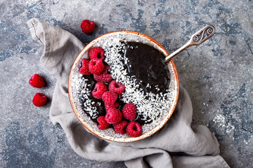 Wall Mural - Activated charcoal smoothie and chia seed pudding bowl, vegan detox dessert with raspberry and coconut milk. Overhead, top view, flat lay