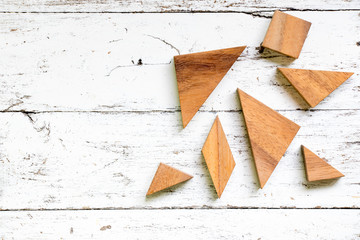 Tangram puzzle in piece wait to complete shape on old white wood background