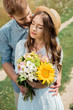© LIGHTFIELD STUDIOS - tender man hugging girlfriend with bouquet of wild flowers in summer field
