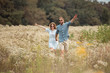 © LIGHTFIELD STUDIOS - happy lovers holding hands while running in field with wild flowers