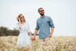 © LIGHTFIELD STUDIOS - portrait of happy lovers in sunglasses holding hands in field with wild flowers