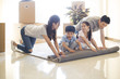 © Blue Jean Images - Happy young family unrolling carpet in new house