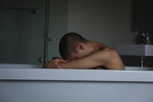 Young Man Sitting In Bathtub At Bathroom