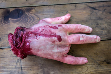 Realistic model of an amputated male hand lies on a dirty wooden table