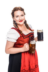 Wall Mural - happy oktoberfest waitress in traditional bavarian dress holding mugs with light and dark beer isolated on white background