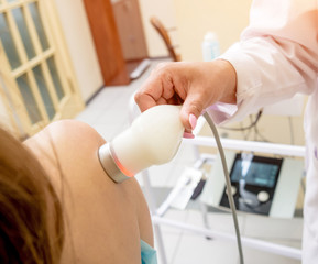 Ultrasound treatment in physical therapy. Doctor using an ultrasound machine to treat the joints and muscles of a patient