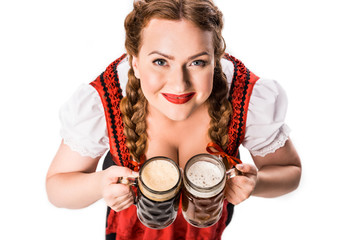 Wall Mural - high angle view of oktoberfest waitress in traditional bavarian dress holding mugs with light and dark beer isolated on white background