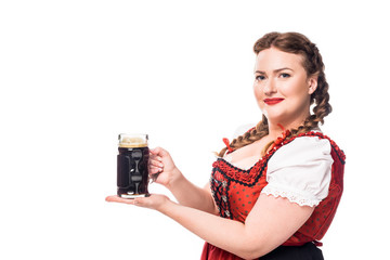 Wall Mural - happy oktoberfest waitress in traditional bavarian dress holding mug of dark beer isolated on white background