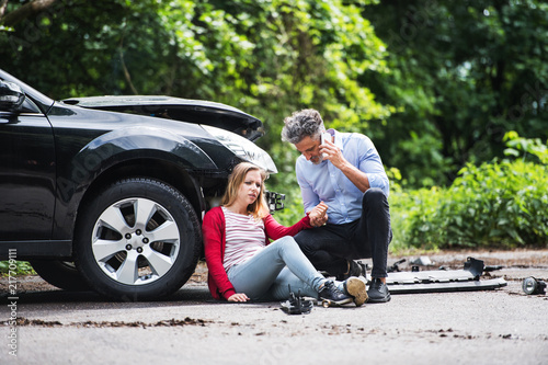 Cuadros en Lienzo Young woman by the car after an accident and a man making a phone call