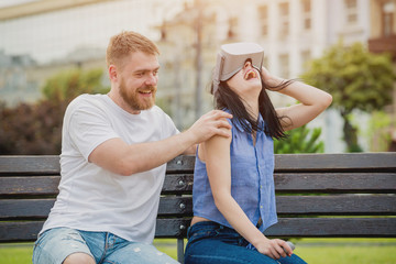 A young couple plays a game using virtual reality glasses on the street.