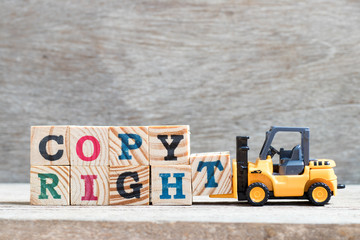 Sticker - Toy forklift hold lette block t to complete word copyright on wood background