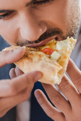 Wall Mural - cropped shot of young businessman eating pizza