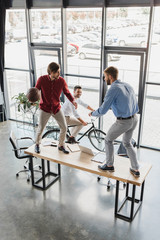 Wall Mural - high angle view of young businessmen having fun with basketball ball at workplace