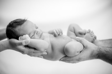 cute newborn baby sleeps in the hands of parents protected and safe - happy family moments for mom a