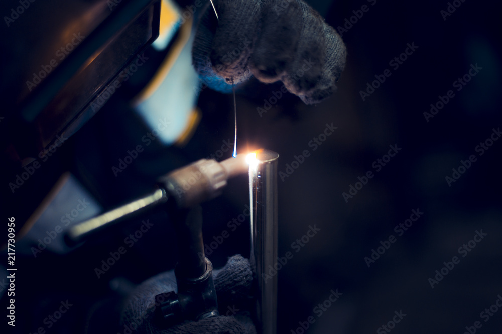 Argon-arc welding welder at the workplace welds the part - obrazy, fototapety, plakaty 