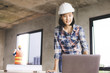 © khwanchai - Engineer woman looking at computer about progressing construction and planing on blueprint