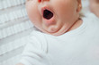 © kaloriya - Infant baby sleeping and yawning on white sheets