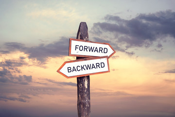 Forward, backward - wooden signpost on sunset background.