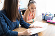 © AntonioDiaz - Girl Reading Notes Held By Teacher At Table In House