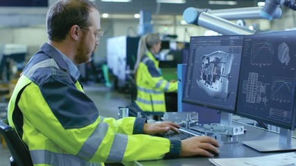 Poster - At the Factory: Mechanical Engineer Works on Computer, Designs in CAD 3D Model of the Engine. In the Background Factory Workers and Manufacturing Process. Shot on RED EPIC-W 8K Helium Cinema Camera.