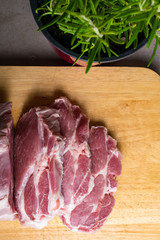 Fresh raw pork chops on cutting wooden board with rosemary