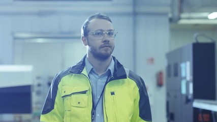 Poster - Industrial Engineer Wearing Protective Clothing Puts on Hard Hat and Walks Through Modern Manufacturing Facility with Automatic Machinery Working in Background.