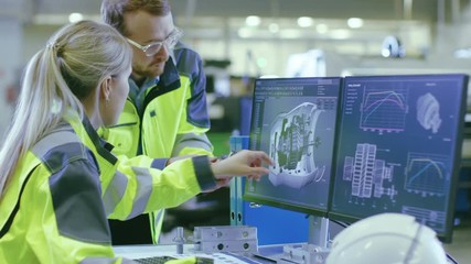 Poster - At the Factory: Male Mechanical Engineer Holds Component while Female Chief Engineer Work on Personal Computer, They Discuss Details of the 3D Engine Model Design.