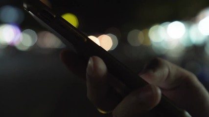 close up man hands using smartphone at night on illumination bokeh color light in night atmospheric 