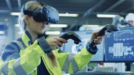 Fototapete - Factory: Female Industrial Engineer Wearing Virtual Reality Headset and Holding Controllers, She Uses VR technology for Industrial Design, Development and Prototyping in CAD Software.