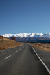 Curved road leading to snow capped mountains