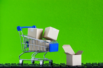 Online shopping, eCommerce or order online concept : Product in a shopping cart and opened box on black keyboard Ordered by customer through the media via internet show that trading is quick and fast.