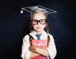 © millaf - Smart child girl student with education book and graduation hat on blackboard background, learning english concept