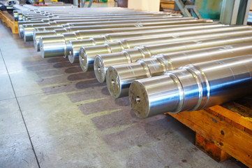 Metal products in the warehouse, large round shafts lie on a wooden rack in the factory in the shop.