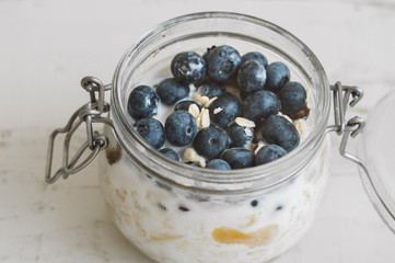 Overnight oats with bluberry soaked in coconut milk in a glass jar. Vegan friendly breakfast. Oatmeal