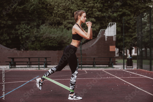 Fotografía Young sporty woman doing exercises with rubber band outdoor