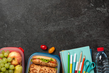 Lunch boxes and school supplies on black